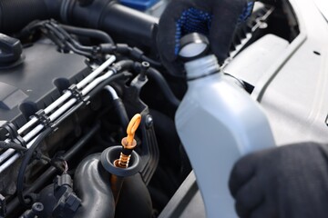Worker checking motor oil level in car with dipstick, closeup