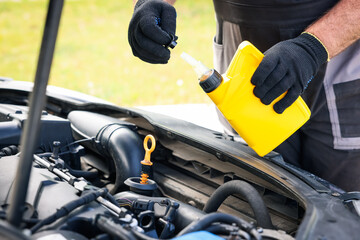 Worker checking motor oil level in car with dipstick, closeup