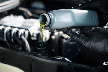Worker pouring motor oil from canister into car engine, closeup