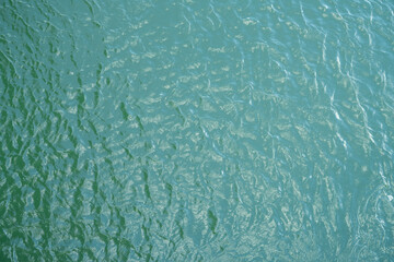 Naklejka na ściany i meble Top view of calm water surface texture with soft natural ripples. Background for eco-friendly design, peaceful concepts, and water sustainability. Aerial view blue green lake surface water background.