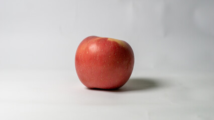 A vibrant red apple sits on a clean white background, showcasing its fresh and healthy appearance.
