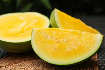 Pieces of ripe yellow watermelon on wicker table, closeup