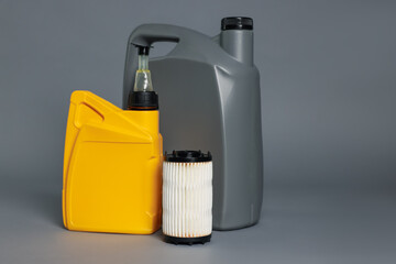 Motor oil in plastic canisters and filter on grey background, space for text
