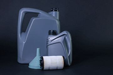 Motor oil in plastic canisters, filter and funnel on dark grey background, space for text