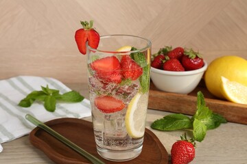 Tasty refreshing drink with strawberries, lemon and mint on wooden table, closeup