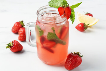 Refreshing drink with strawberries, ice and mint on white table, closeup