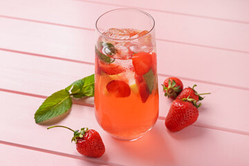 Refreshing drink with strawberries, mint and ice on pink wooden table, closeup