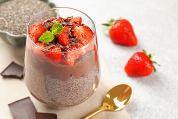 Delicious chocolate pudding with chia seeds, strawberries and mint on light grey table, closeup. Space for text