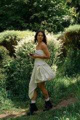 Curly haired young woman enjoying a sunny summer day in a white dress outdoors