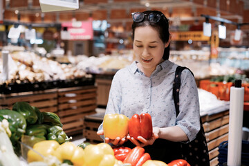 Asian woman picking vegetables in supermarket