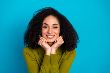 Smiling young woman with natural curly hair in casual style against blue background, showcasing...