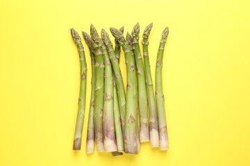Fresh ripe raw asparagus on yellow background, top view