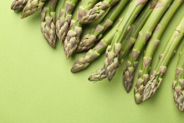 Fresh ripe raw asparagus on green background, closeup. Space for text