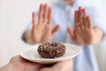 Gluten free diet. Man refusing from donut indoors, selective focus