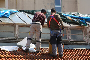 Ouvriers qui réparent des carreaux cassés sur une verrière