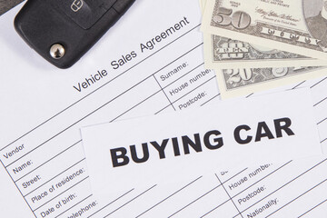 Car key, dollar banknotes and vehicle sales agreement. Inscription buying car. Sales, purchases of...