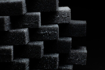 pile of black sponge foam sheet material arranged in cubes. porous and rough texture for design...