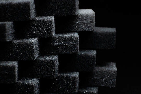 pile of black sponge foam sheet material arranged in cubes. porous and rough texture for design background