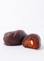 Dark chocolate candy with whole almond in fruit filling on white background