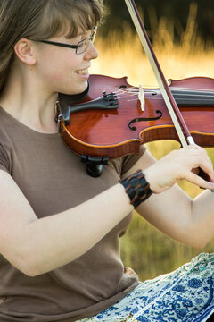 Close up portrait of girl playing violin outdoors in a paddock
