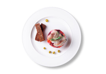 Flat lay shot of traditional Russian vinaigrette salad with diced vegetables and herring fillet, served with rye croutons and green peas. Clean white plate on white background