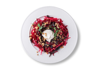 Healthy shredded beet salad with chopped prunes and walnuts, served with a dollop of sour cream and microgreens on top. Fresh, vegetarian and full of flavor. Photographed from above on a clean white
