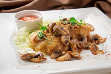 Traditional crispy potato pancakes served with sautéed mushrooms and caramelized onions, garnished with microgreens. Presented on a white plate with a side of red sauce and fresh lettuce.