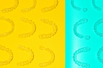 Invisible orthodontic cosmetic aligners on a colored background, aligners, plastic braces. Modern...