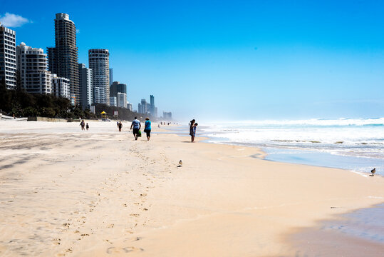People walking along Gold Coast beach in summer with city in background