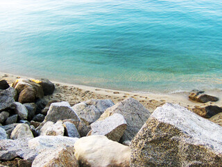 A breathtaking view of the serene seashore in Tropea, Italy, where gentle, light waves caress the pristine sandy beach under a radiant Mediterranean sun. The turquoise waters shimmer with clarity.