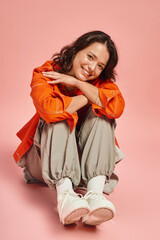 Stylish young woman embraces her individuality in vibrant attire against a playful backdrop