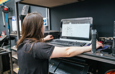 Young female mechanic analyzing parts diagram on computer in professional auto workshop