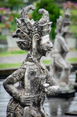 Intricately carved guardian statue in Balinese temple garden, symbolizing mythology, protection,...