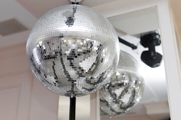 Shiny silver disco ball hanging from the ceiling, illuminated by a spotlight.