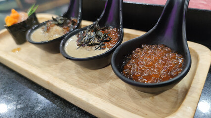 Delicious close up of Japanese appetizer featuring luxurious fresh salmon roe ikura and creamy crab paste. Gourmet fish dish served on spoon for delightful tasting