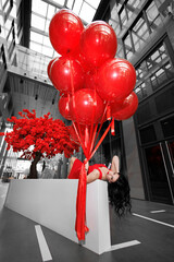 Young woman in a red dress with large helium balls.
