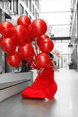 Young woman in a red dress with large helium balls.