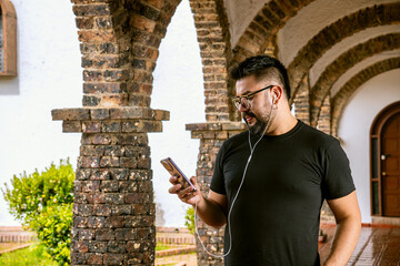 A college student listening, dancing, and enjoying music playing on his cell phone in the...