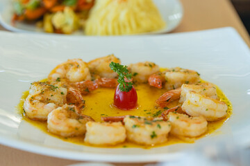 Cooked shrimp in buttery garlic sauce with parsley and cherry tomato