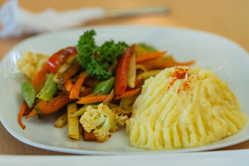 Mashed potatoes with sautéed vegetables and parsley garnish