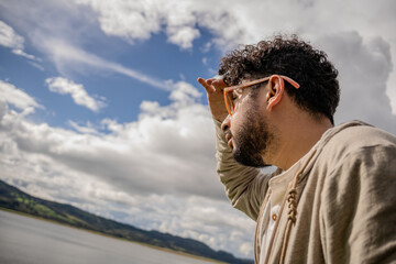 Hipster Latino man in a red striped shirt, impressed by Lake Guatavita. Concepts of emotions,...