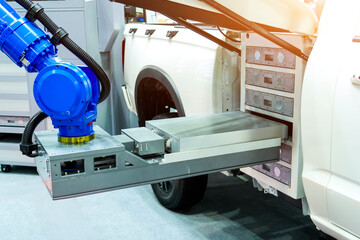 Robotic arm automatically replaces loads unloads charged lithium ion batteries in an electric light...