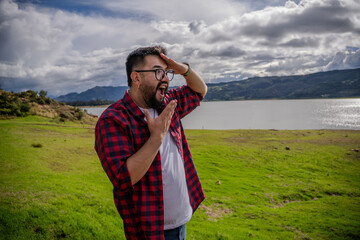 Hipster Latino man in a red striped shirt, impressed by Lake Guatavita. Concepts of emotions,...