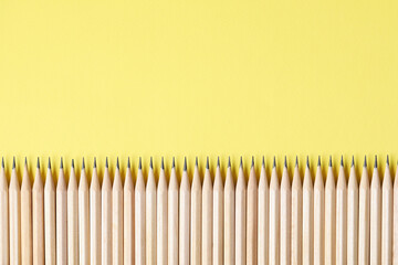 Many graphite pencils on yellow background, flat lay. Space for text