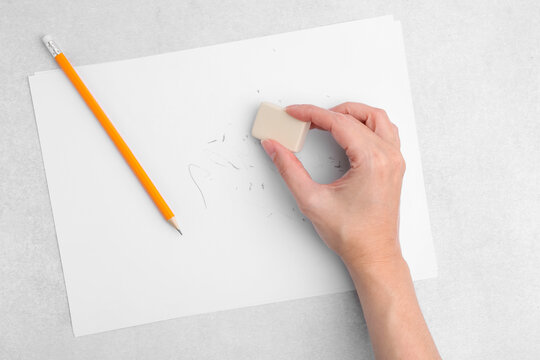 Woman with graphite pencil, eraser and paper sheet at light table, top view