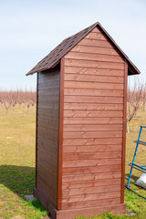Wooden country new toilet with a roof on a farm plot. Toilet installation