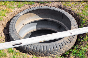 A pit for an outdoor village toilet with walls made of rubber tires. Making a toilet on a personal plot