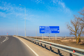 a sign indicating the direction of travel on a road on a spring day