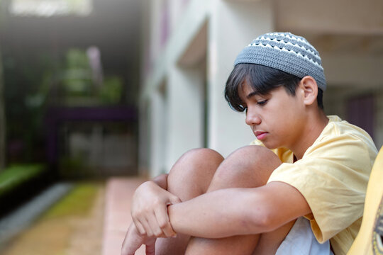 A young boy in a striped shirt gazing out the window with a curious and thoughtful look, seated indoors. Moment of imagination, dreaming, or waiting.