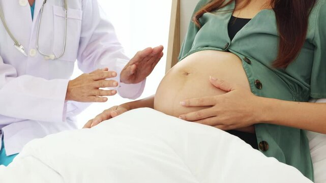 Senior doctor uses stethoscope to check fetus' health, measure fetal heart rate while moving and assess fetus and mother's health : Happy  excited mother visits doctor before giving birth.